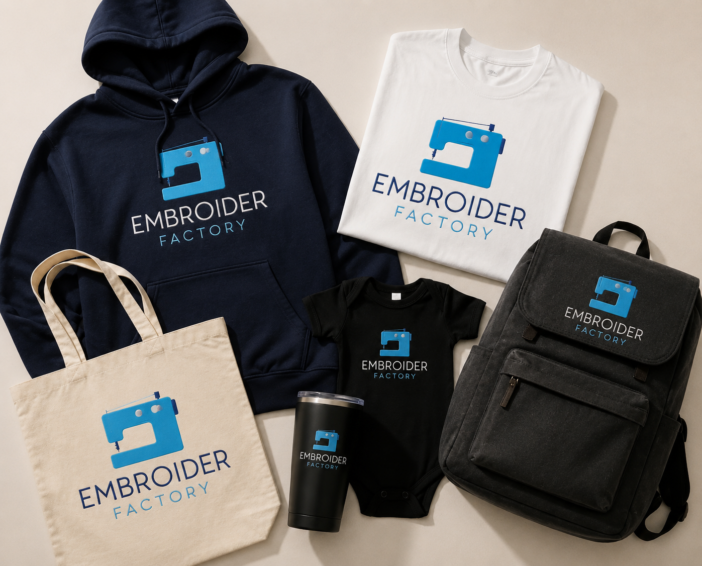 Embroider Factory custom apparel collection: navy hoodie, white t-shirt, canvas tote bag, black baby bodysuit, insulated tumbler and backpack, each with the Embroider Factory logo